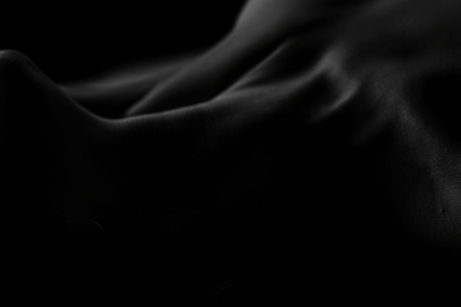 Abstract curves and shadows of human skin create a dramatic contrast against a dark background.