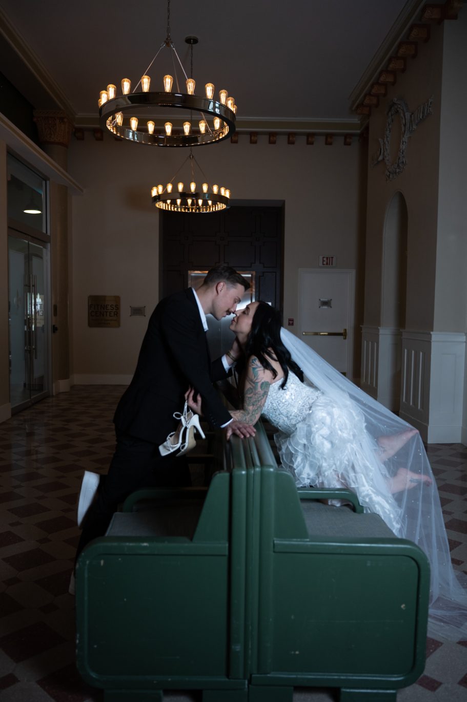 Bride and groom leaning toward each other, surrounded by elegant decor and soft lighting.