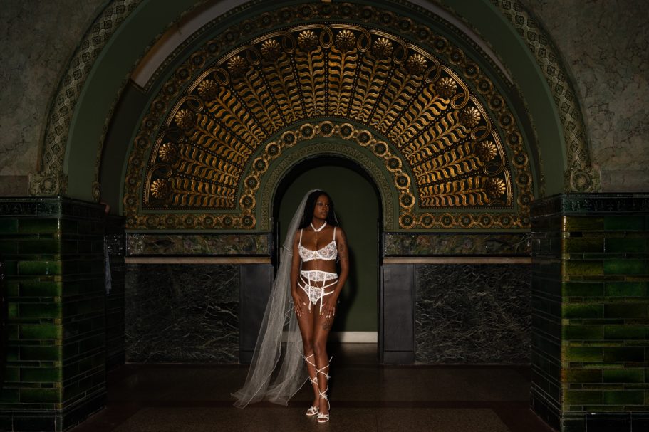 A woman in elegant attire walks through a beautifully decorated archway.