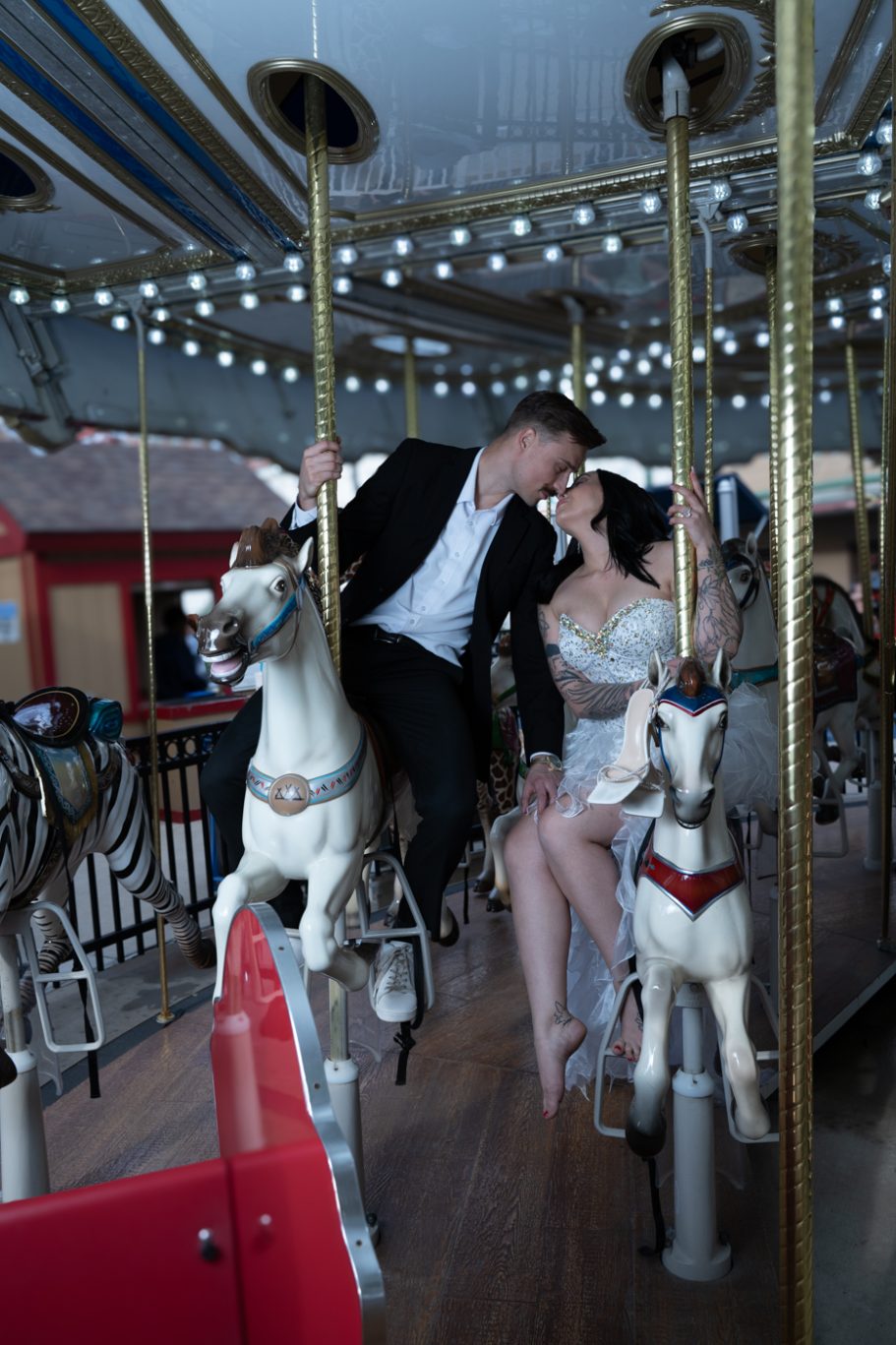 Couple in formal attire sharing a romantic moment on a carousel.
